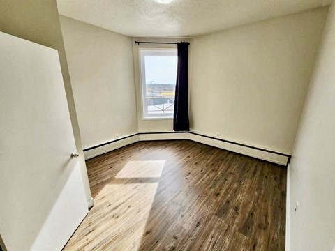 an empty living room with wood flooring and a window