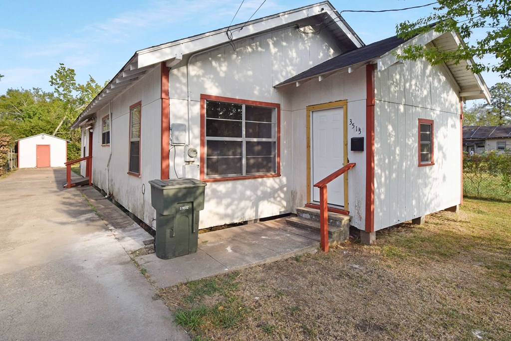 a small white house with red trim and a driveway