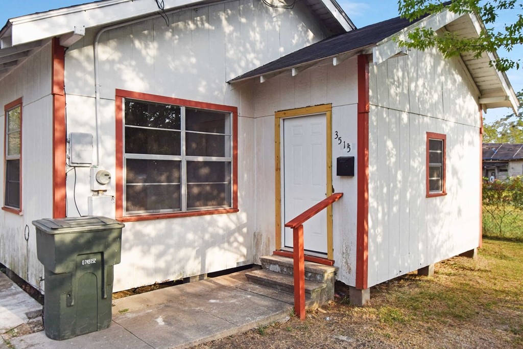 the front of a white house with a door and a window