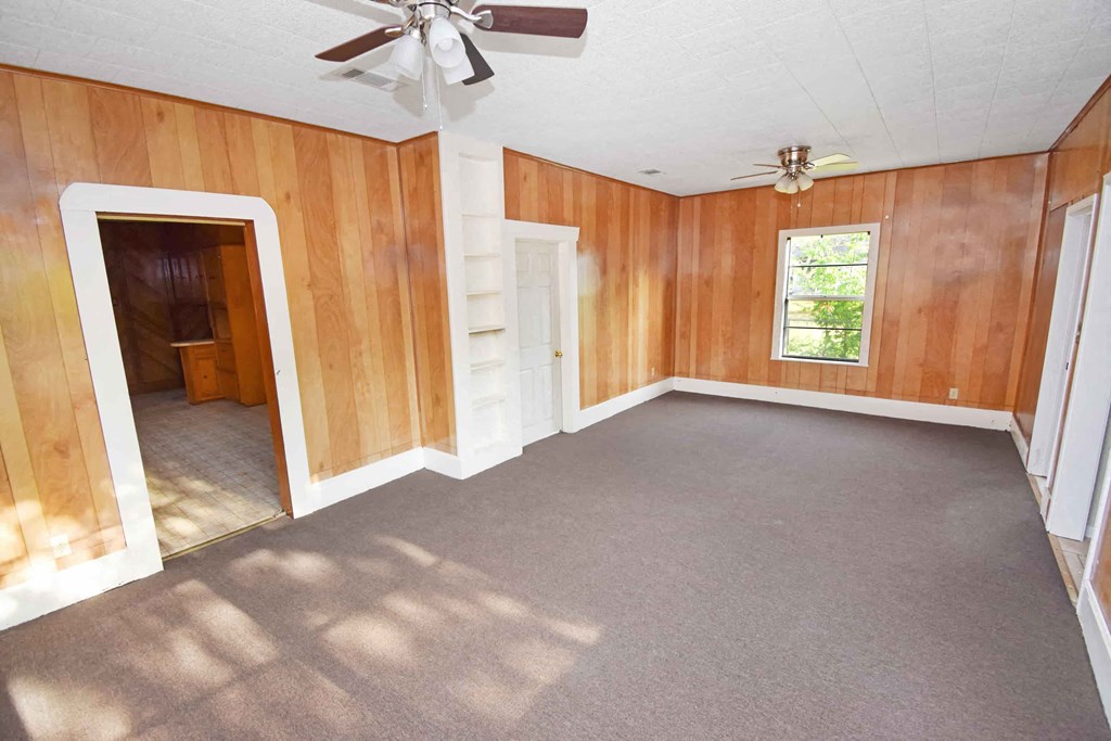 an empty living room with a ceiling fan