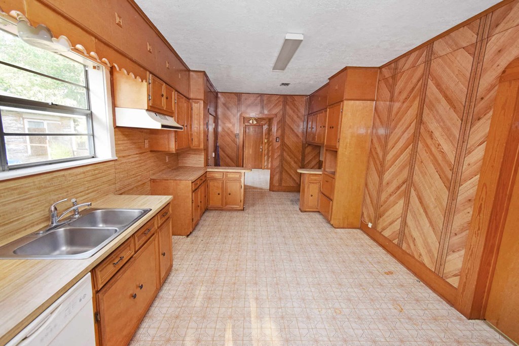 an empty kitchen with wooden cabinets and a sink