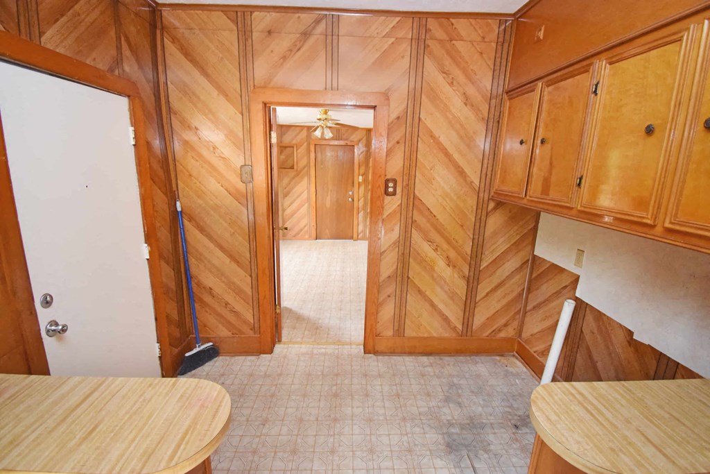 a small kitchen with wooden cabinets and a door to a hallway