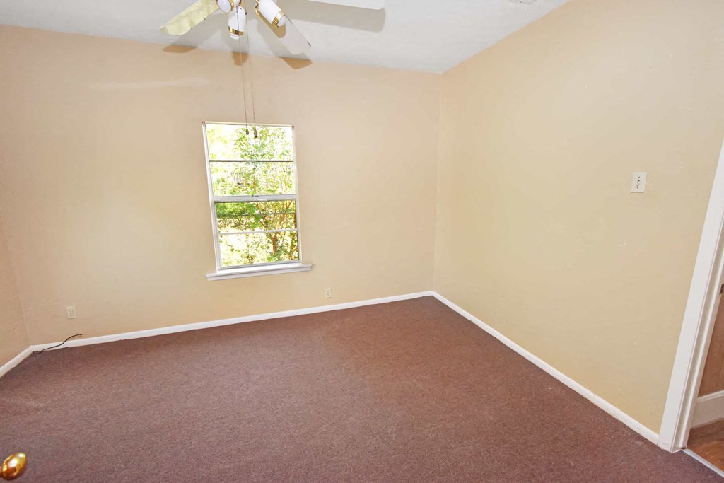 an empty room with a window and a ceiling fan