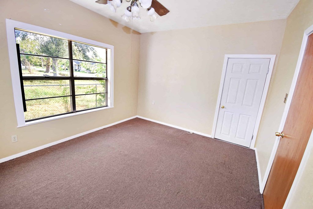 an empty bedroom with a window and a door