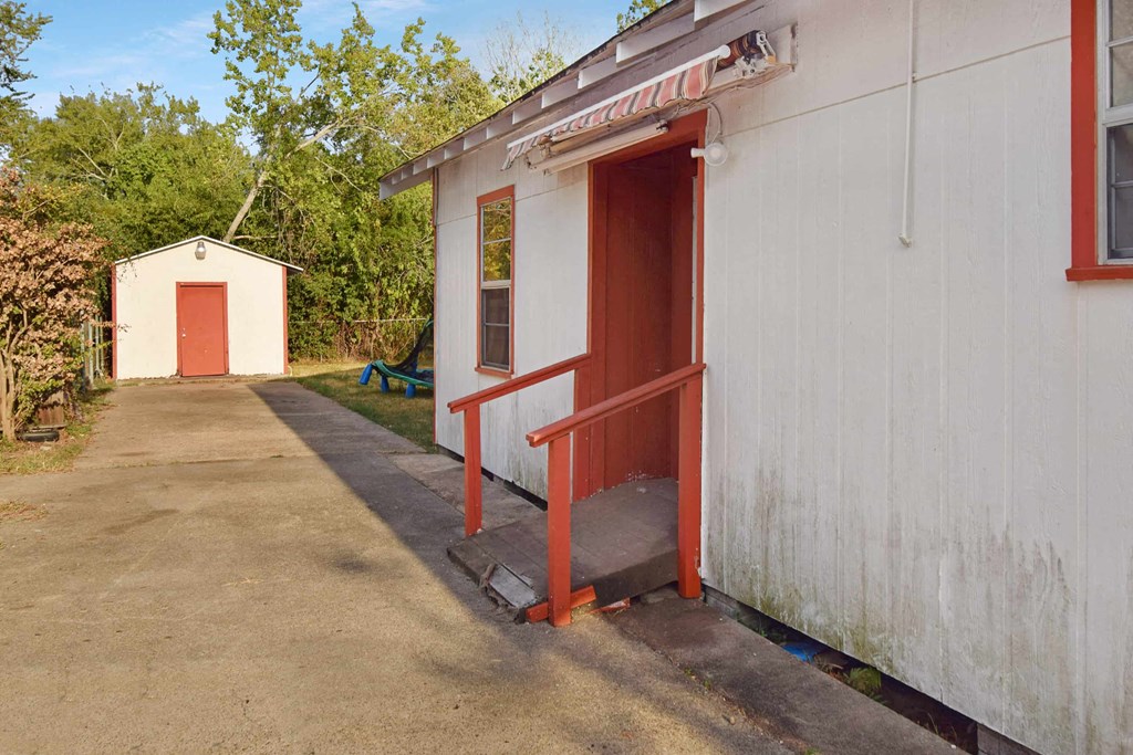 the front entrance of a small building with a red door