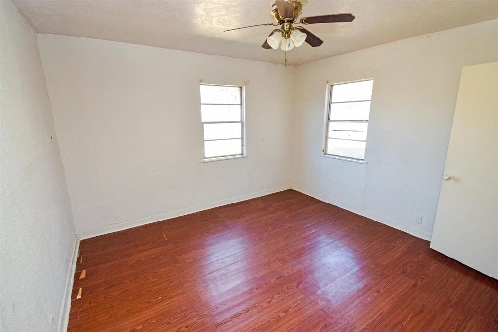 an empty room with wooden floors and a ceiling fan