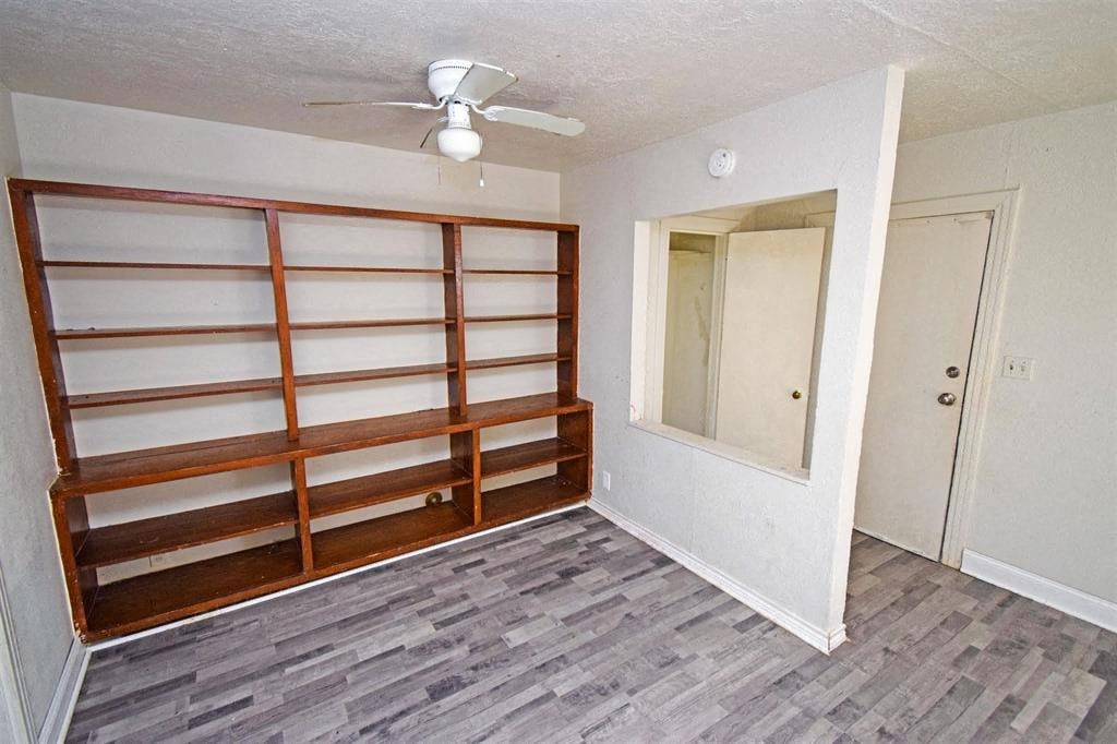 an empty living room with a wood floor and a ceiling fan