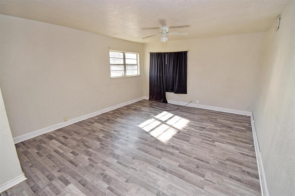 an empty living room with wood flooring and a ceiling fan