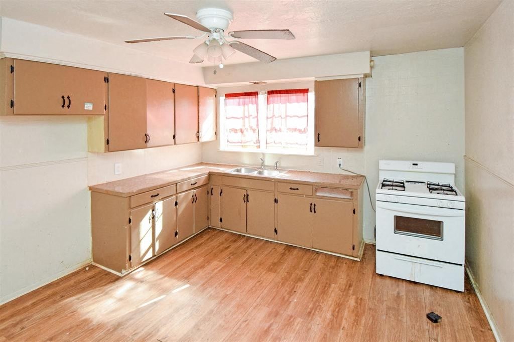 an empty kitchen with a stove and a ceiling fan
