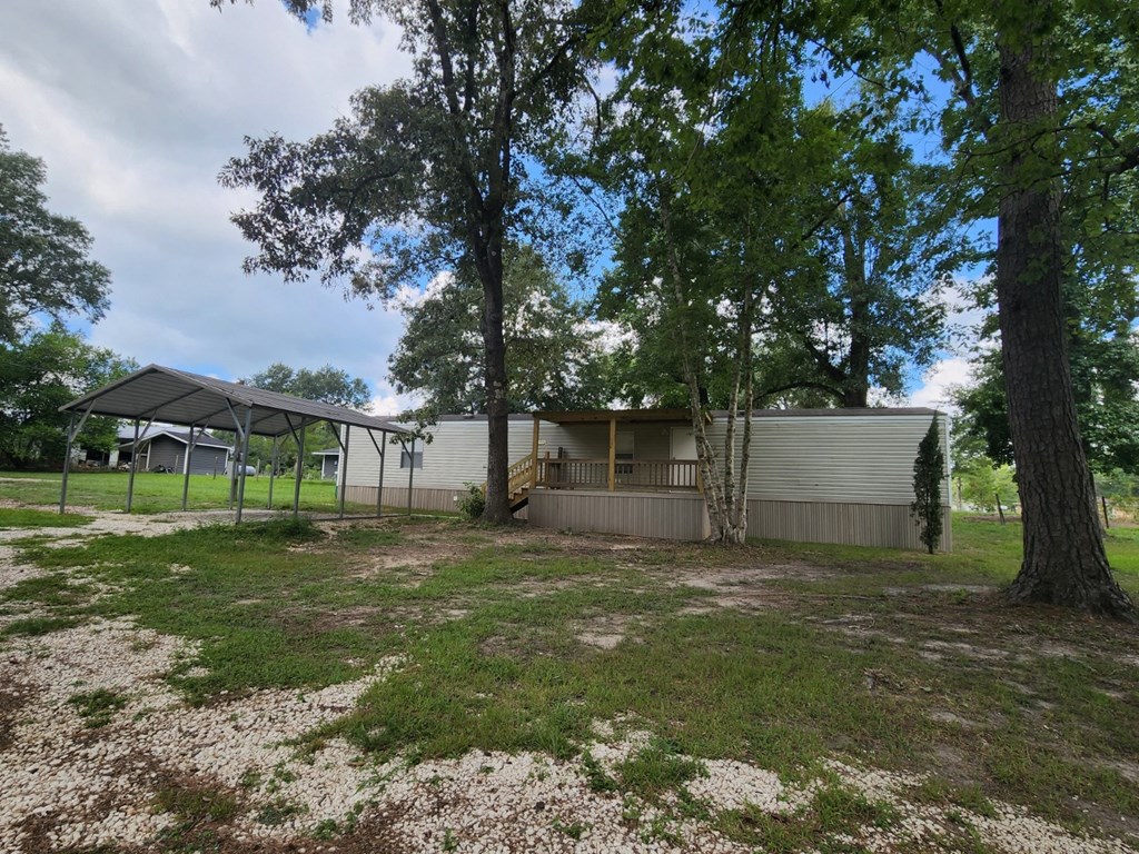 the exterior of a white house with a yard and trees
