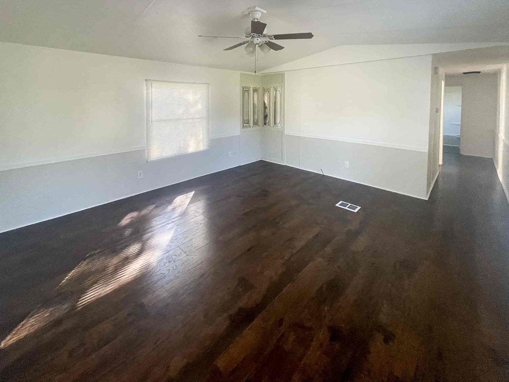 an empty living room with hardwood floors and a ceiling fan