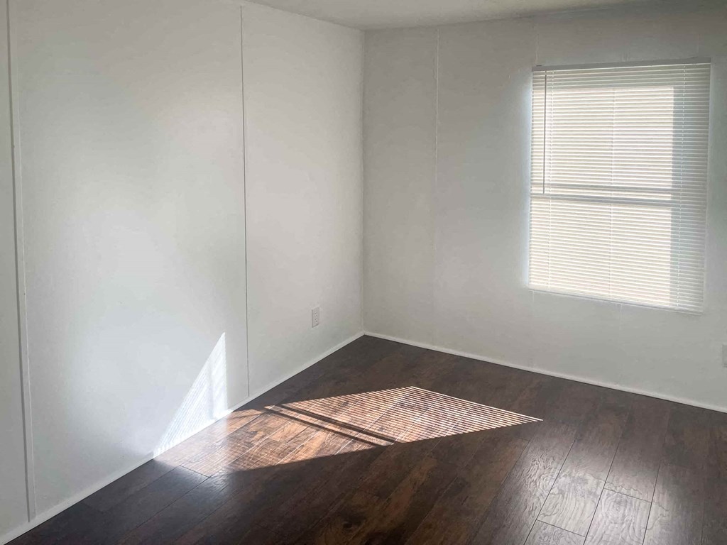 a room with white walls and wooden floors and a window