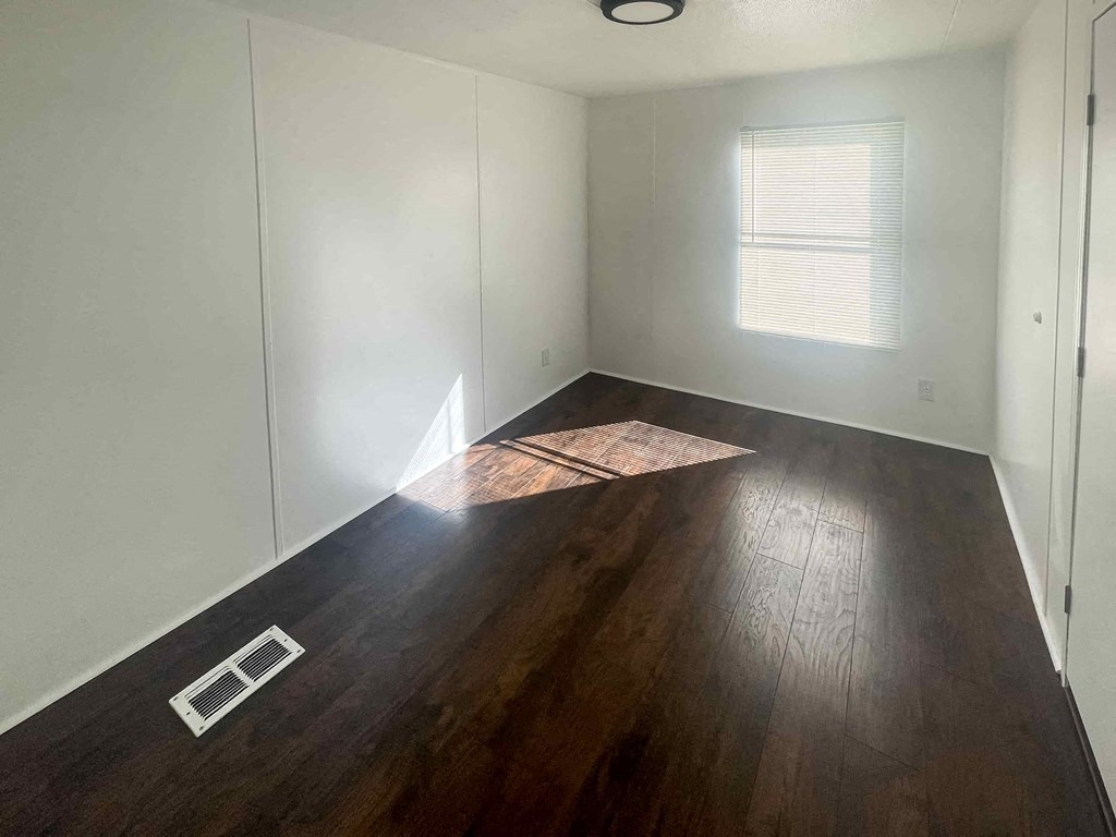 a room with hardwood flooring and white walls and a window