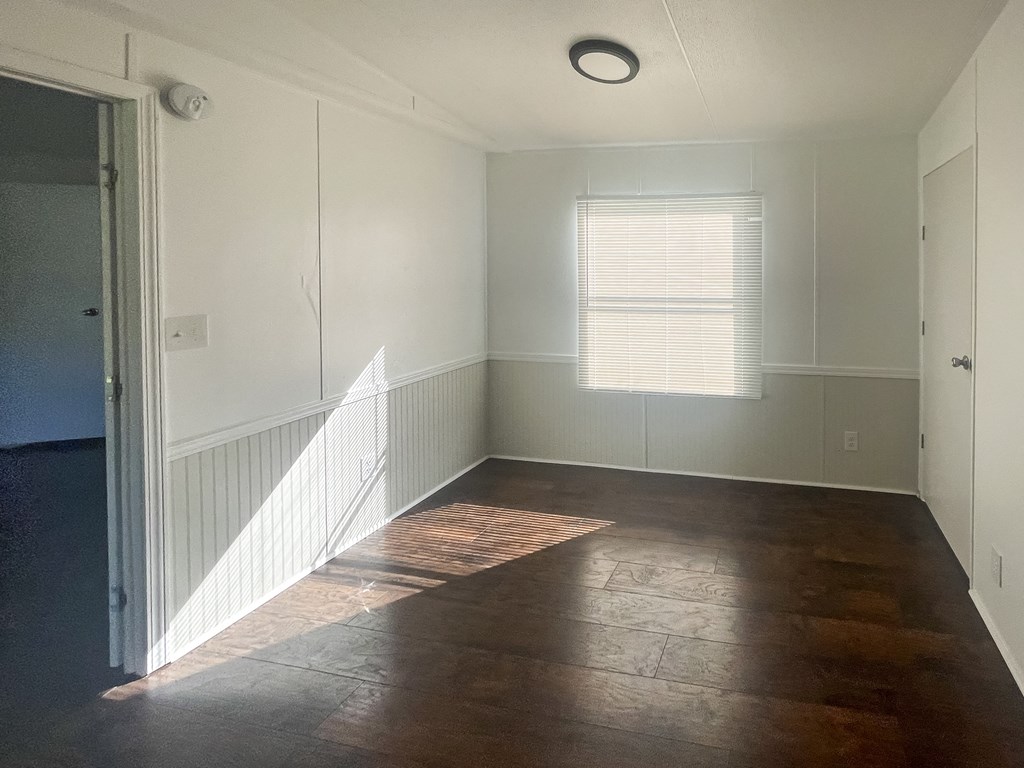 an empty living room with wood floors and a window