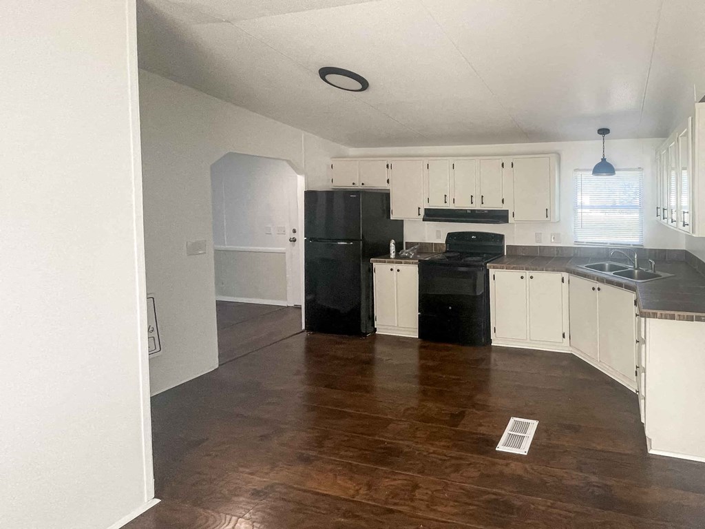 an empty kitchen with white cabinets and black appliances