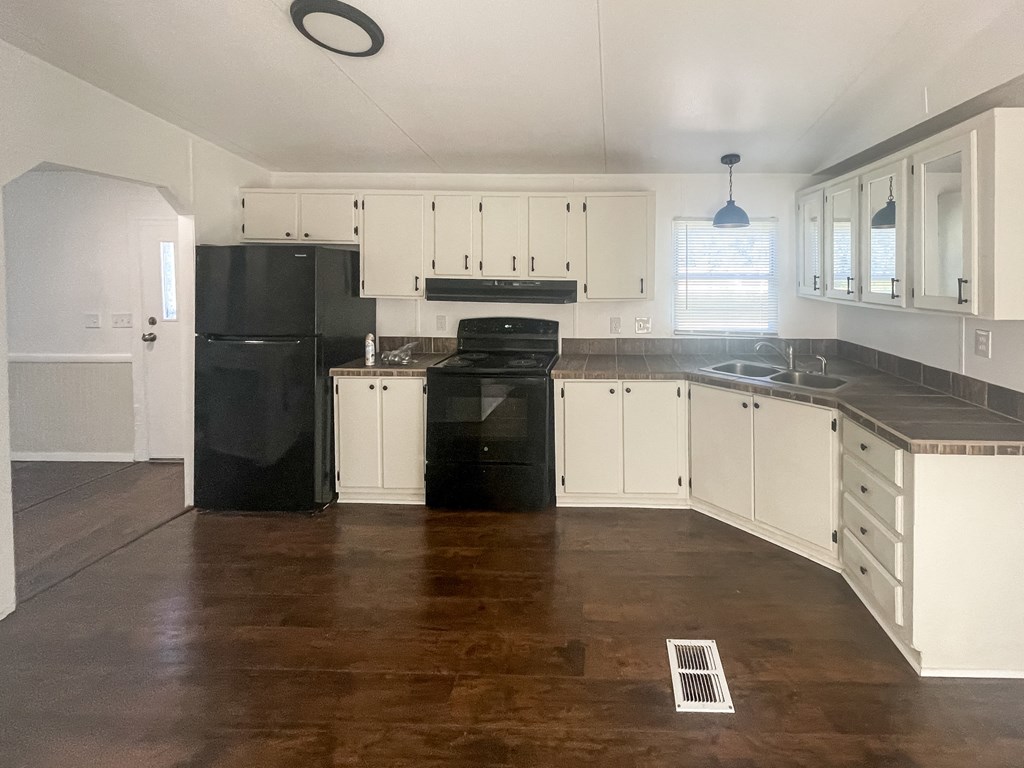 an empty kitchen with white cabinets and black appliances