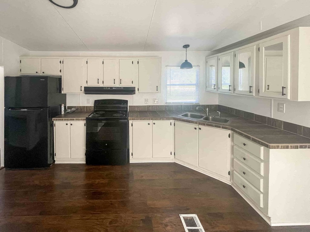 an empty kitchen with white cabinets and black appliances
