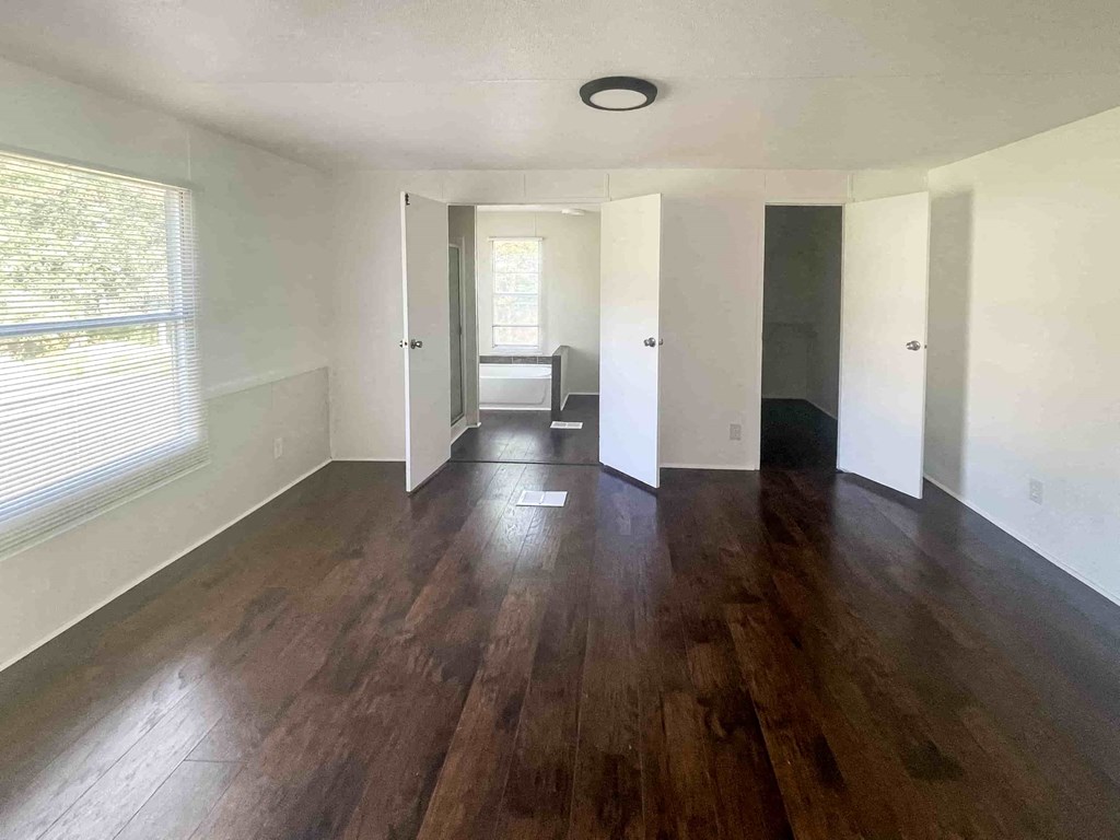 an empty living room with hard wood floors and a window