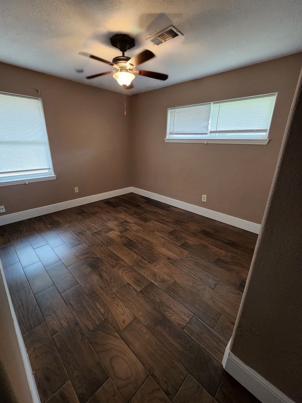 a empty room with wood floors and a ceiling fan