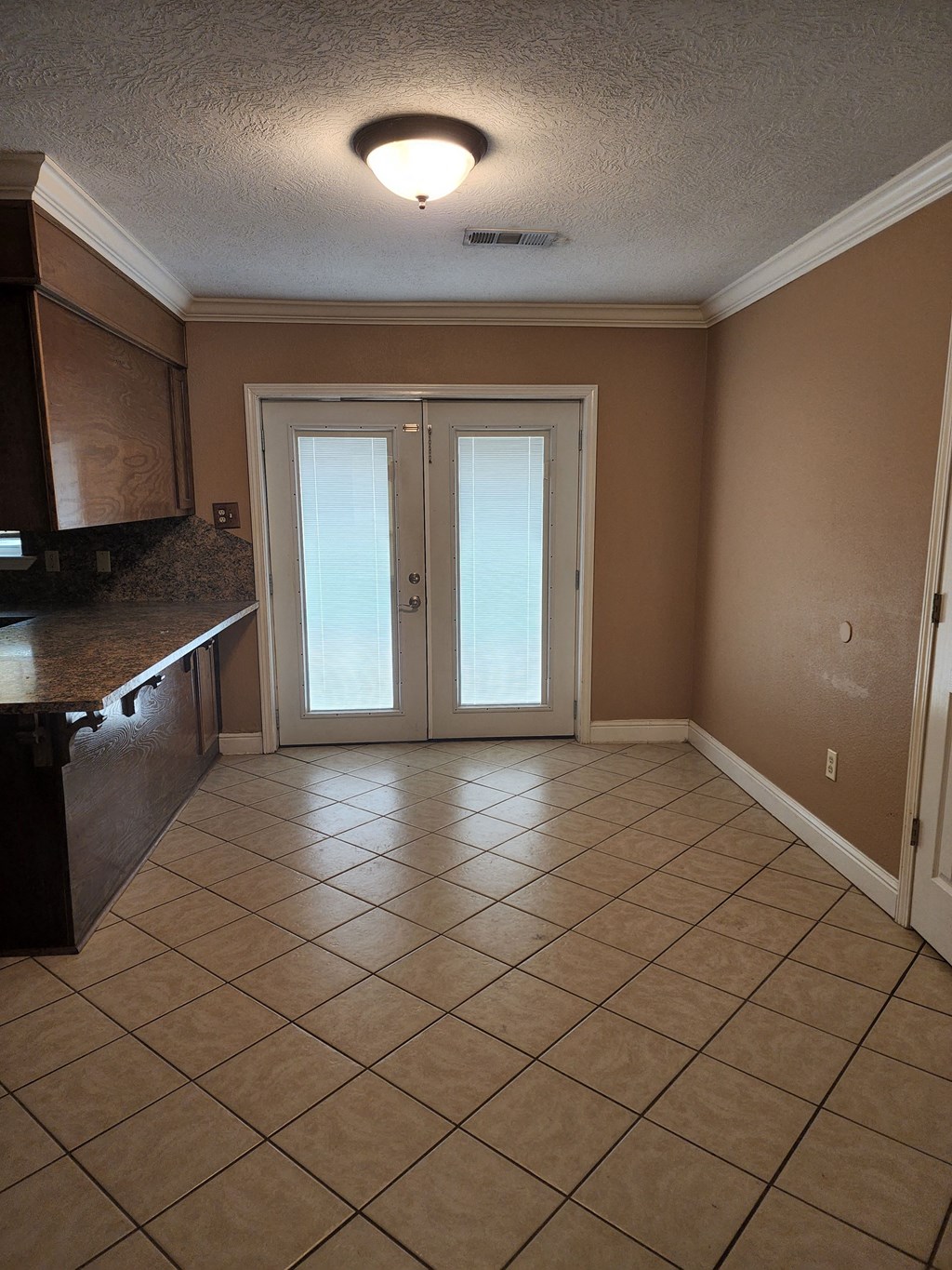 an empty living room with a tiled floor and two glass doors