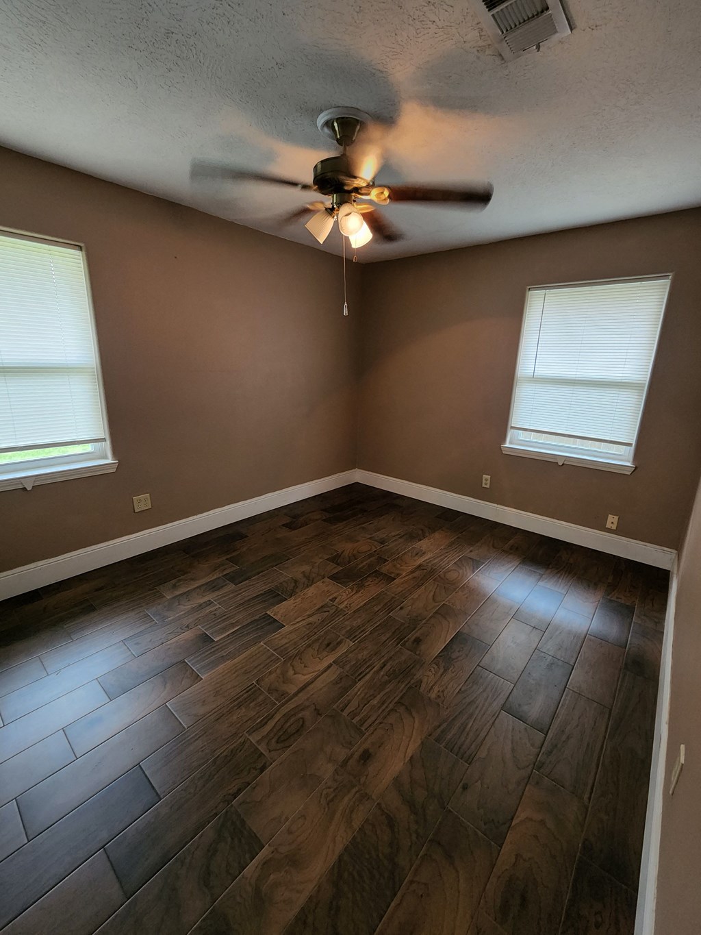 a living room with wood floors and a ceiling fan