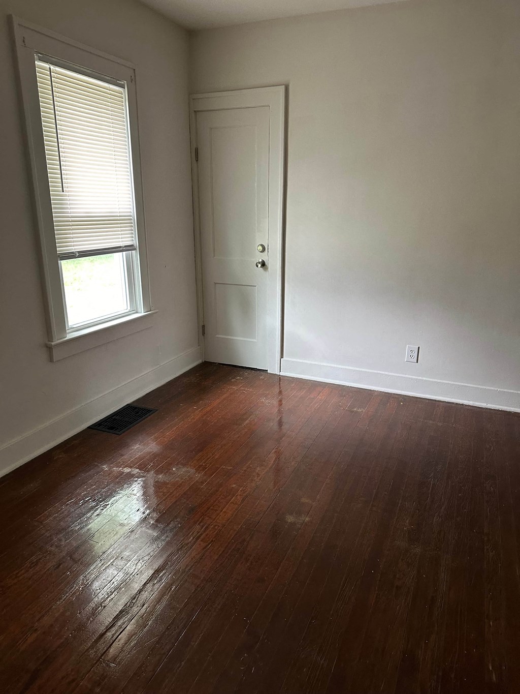 an empty room with wood floors and a door and a window