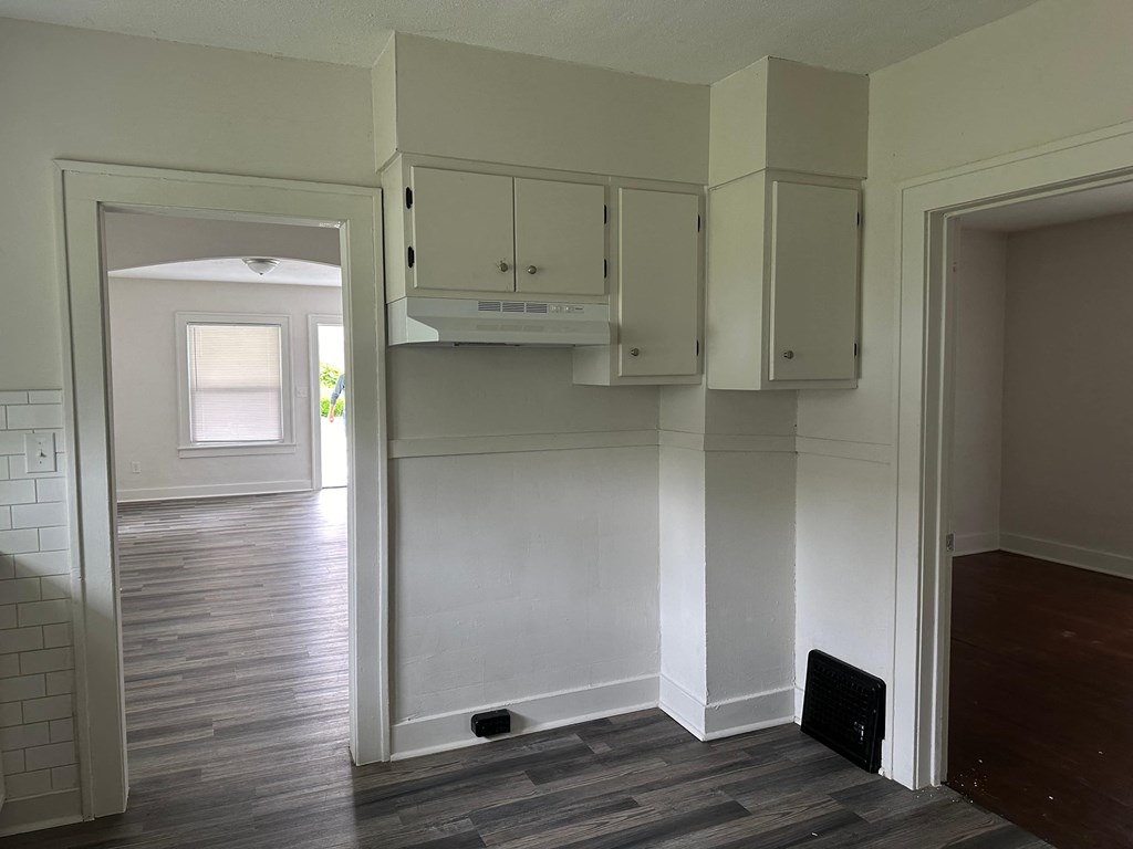 an empty kitchen with white cabinets and a wood floor