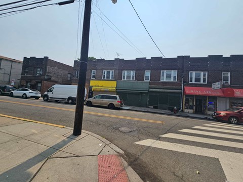 A street view with cars, buildings, and a crosswalk.