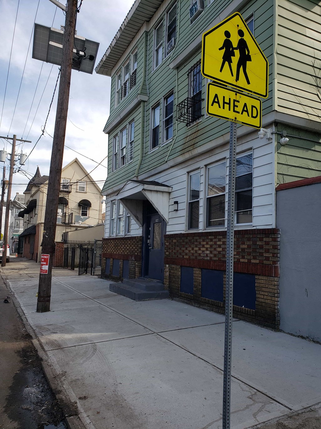 A pedestrian crossing sign is displayed on a pole on a street.