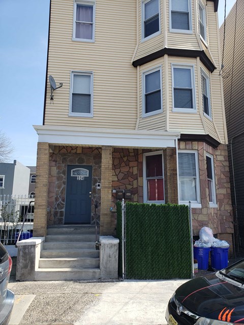 A two-story house with a blue door and a stone wall.