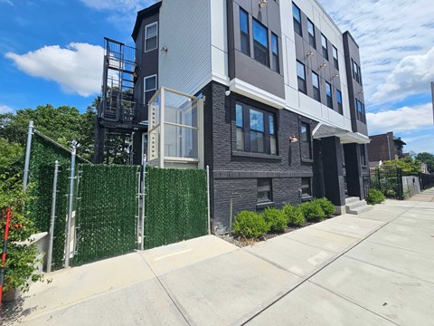 an apartment building with a sidewalk and a fence