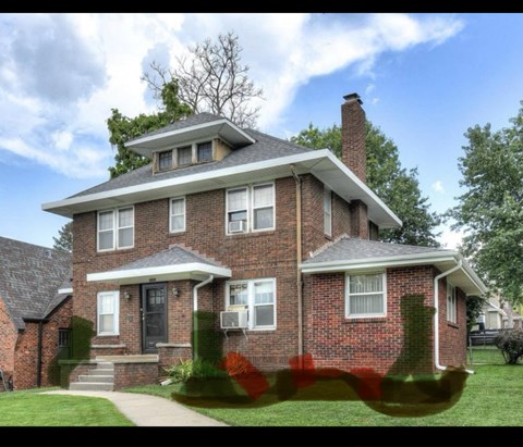A brick house with a black door and a chimney.