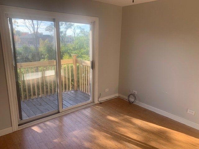 A room with a wooden floor and a sliding glass door leading to a deck.