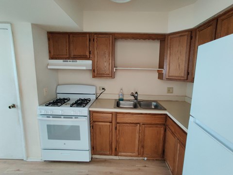 A white stove and sink in a kitchen with wooden cabinets.