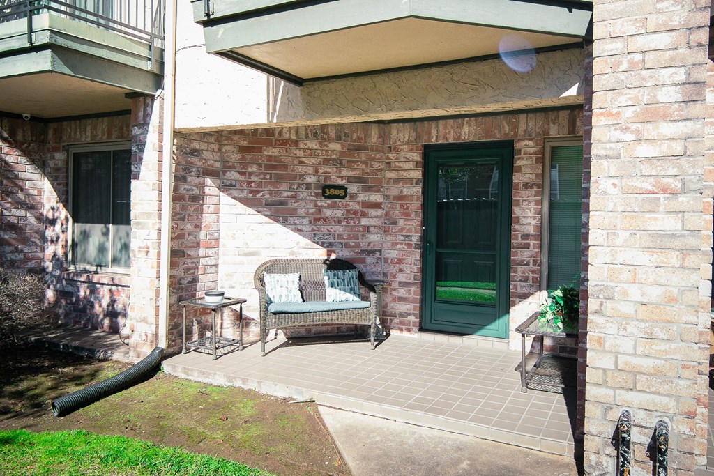 the front porch of the house has a chair and a table