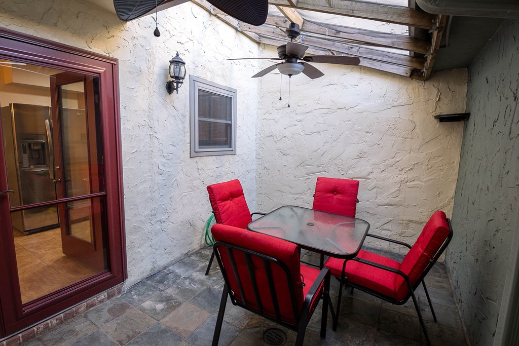 a patio with a table and chairs and a ceiling fan