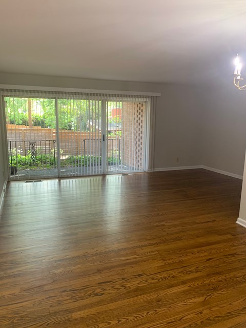 A room with wooden floors and a sliding glass door leading to a backyard.