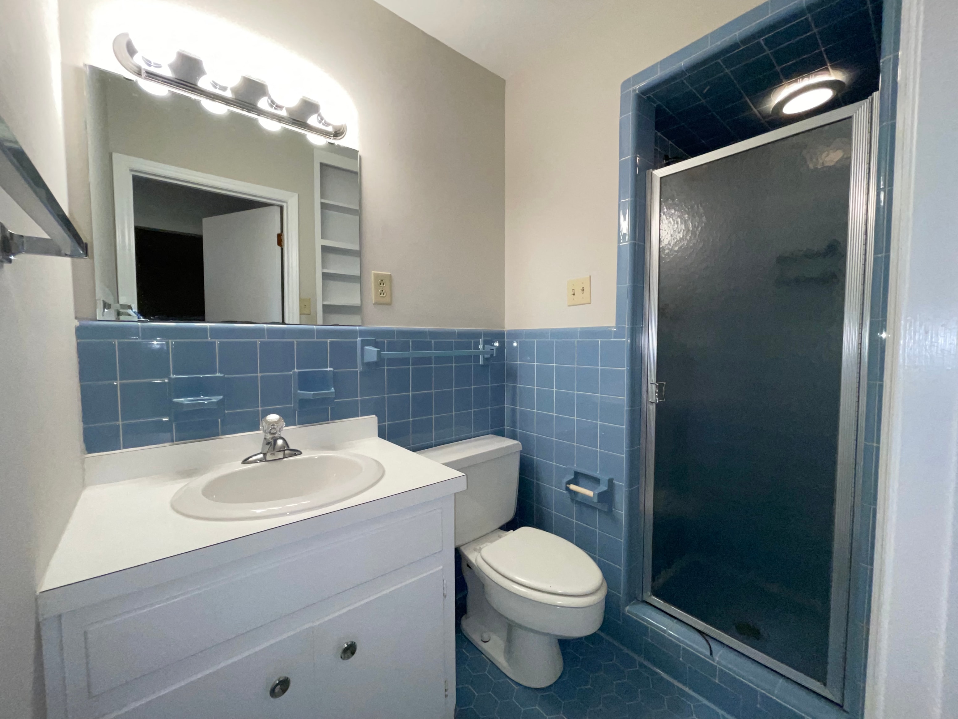 a blue and white bathroom with a shower toilet and sink