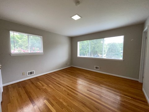 an empty living room with wood floors and two windows