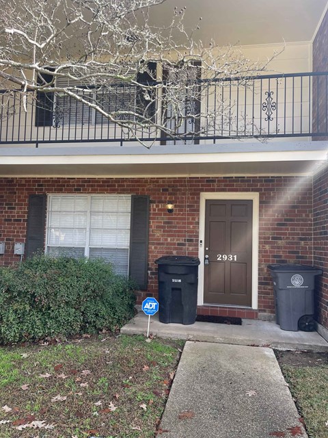 a brick house with a brown door and a balcony