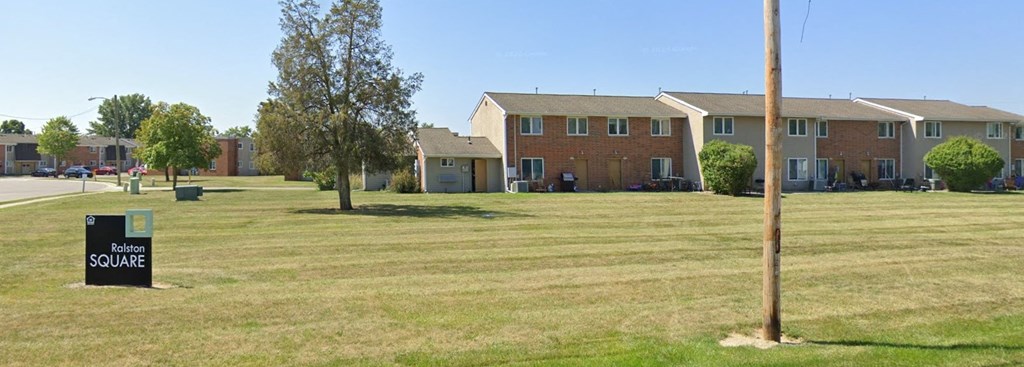 a sign in the grass in front of a row of houses