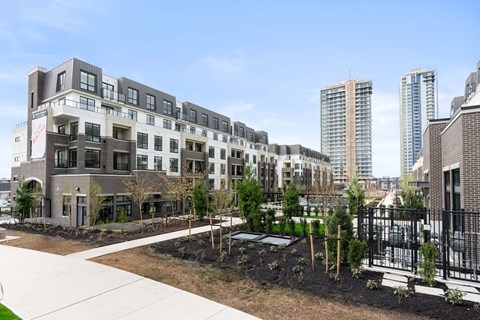 A modern building with a black fence and a garden in front.