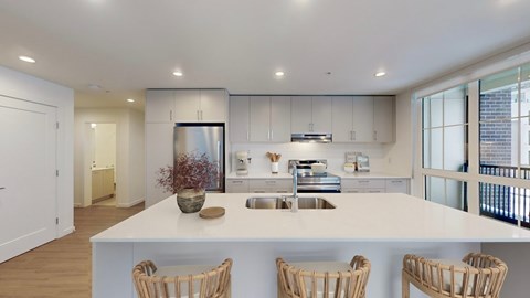 A modern kitchen with a large island and chairs.