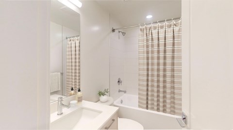 A white bathroom with a sink, mirror, and shower.
