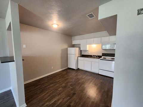 a kitchen with white appliances and a wooden floor