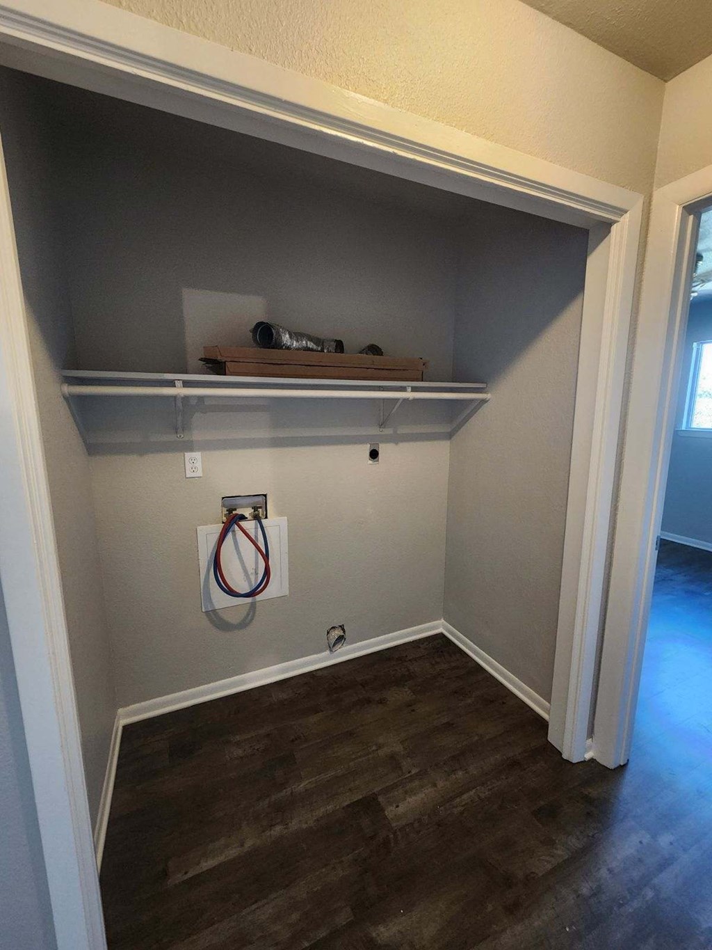 a small room with a wood floor and a closet with shelves