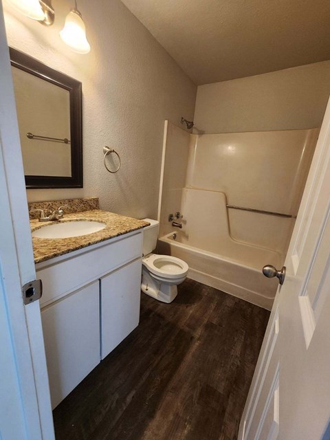 A bathroom with a toilet, sink, and mirror.