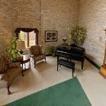 a living room with a piano and a green rug