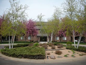 an office building with trees and plants in front of it
