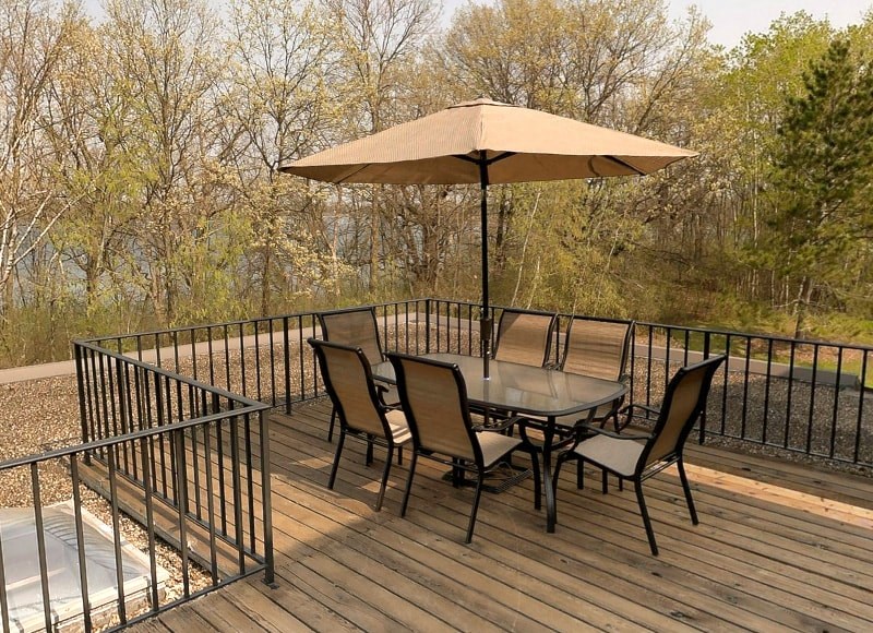 a patio table with an umbrella on a wooden deck
